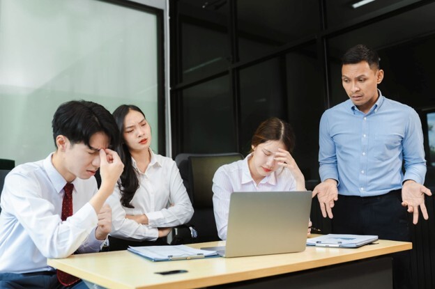 A team experiences workplace tension during a meeting, highlighting how DISC communication styles can help improve understanding and collaboration between different leadership personalities.
