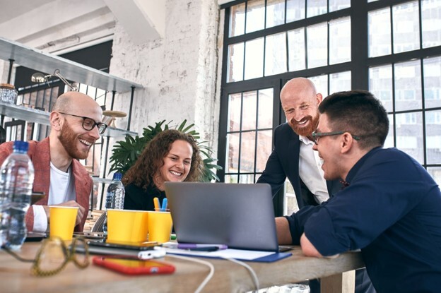 A team collaborates around a laptop during a recruitment discussion, demonstrating how DISC team training can support better hiring decisions and team compatibility.